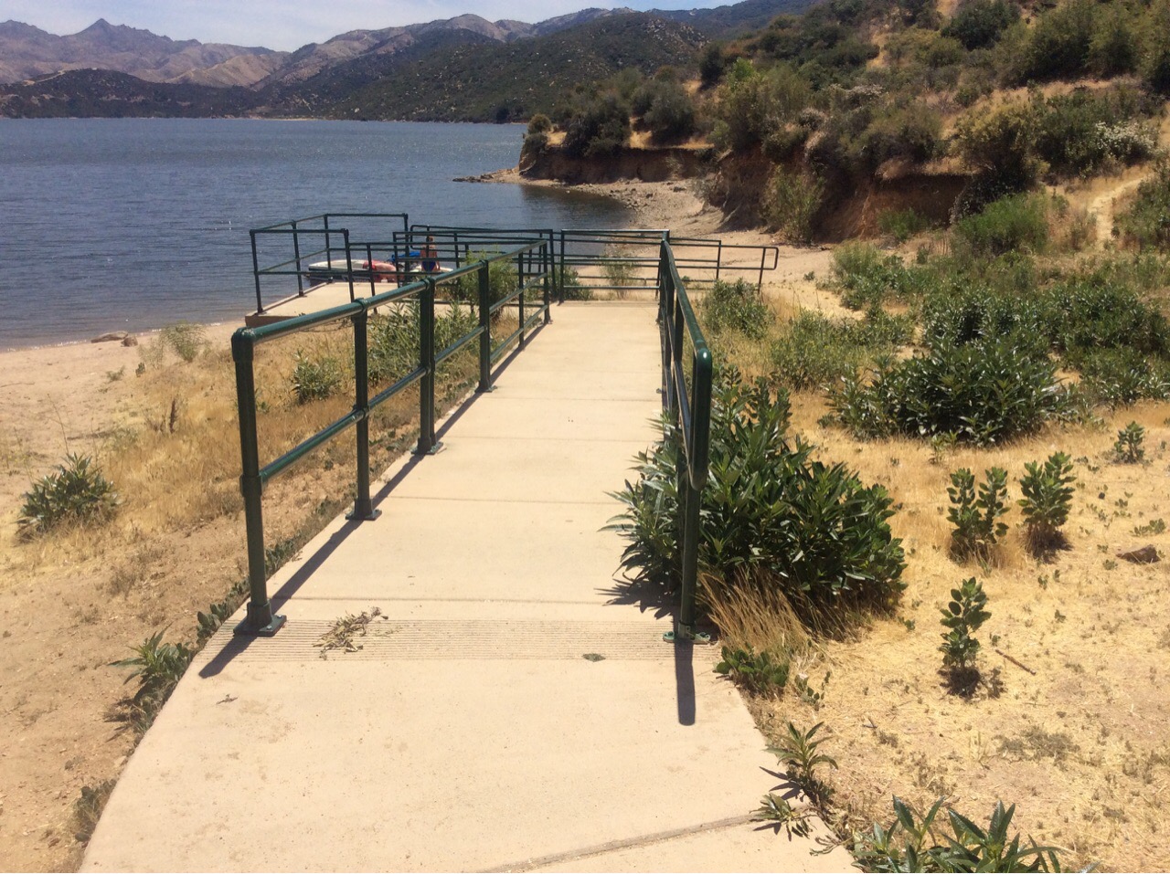 Concrete path with green railings leading toward the shoreline at Chamise picnic area on Silverwood Lake